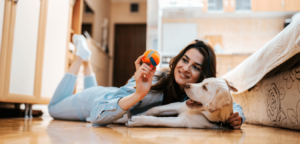 Woman playing with dog on floor at apartment