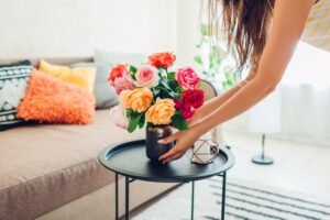 Woman putting flower pot on small coffee table
